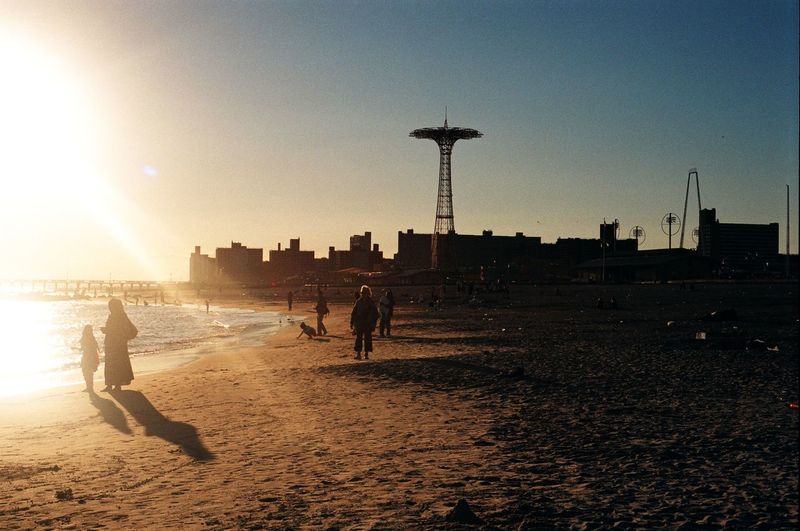 Silhouette people at coney island beach during sunset