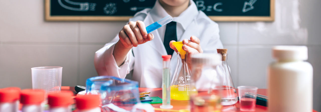 Midsection of boy examining chemical in classroom