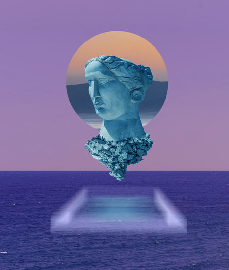Close-up of statue against sea at sunset