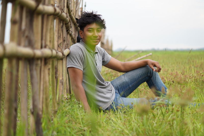 Portrait of smiling young man sitting on field