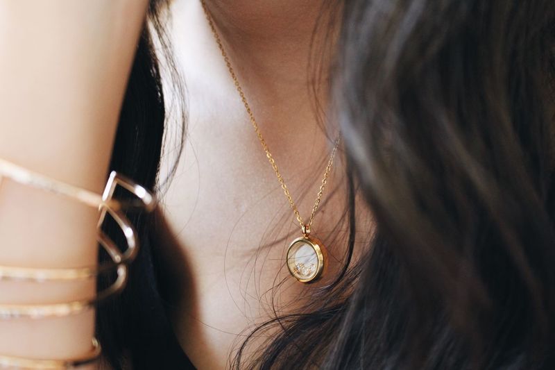 Midsection of woman wearing gold chain with pendant