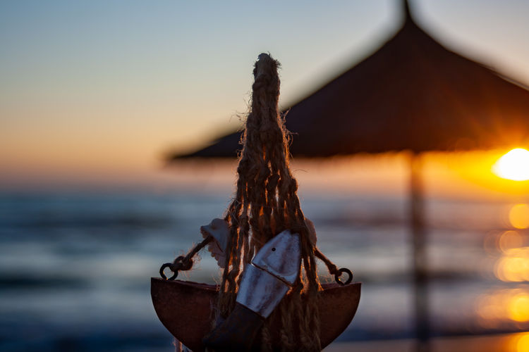 Close-up of rope on beach against sky during sunset