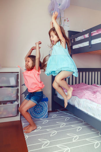 Siblings jumping from bed at home