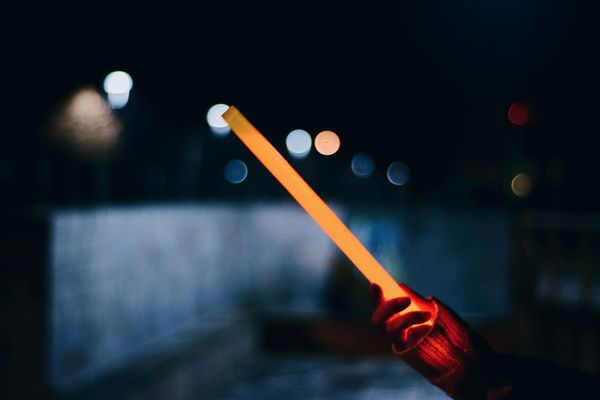 Cropped hand holding laser sword at night