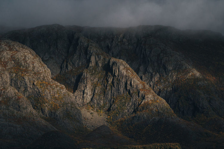 Scenic view of rocky mountains against misty sky