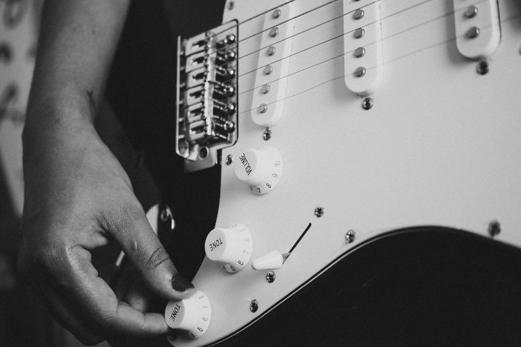 Hand of woman adjusting knobs on electric guitar