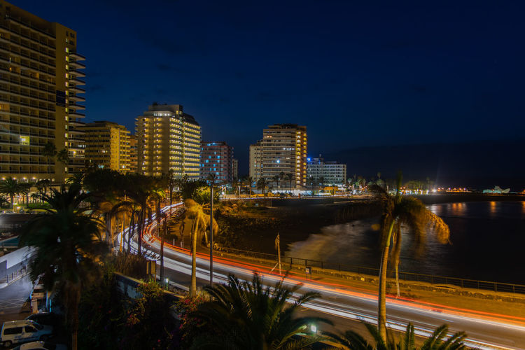 Illuminated city by buildings against sky at night