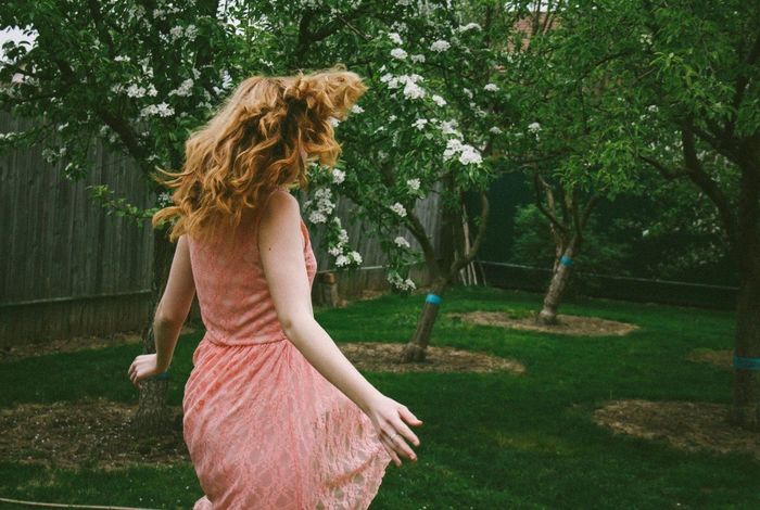 Side view of woman tossing hair in the lawn