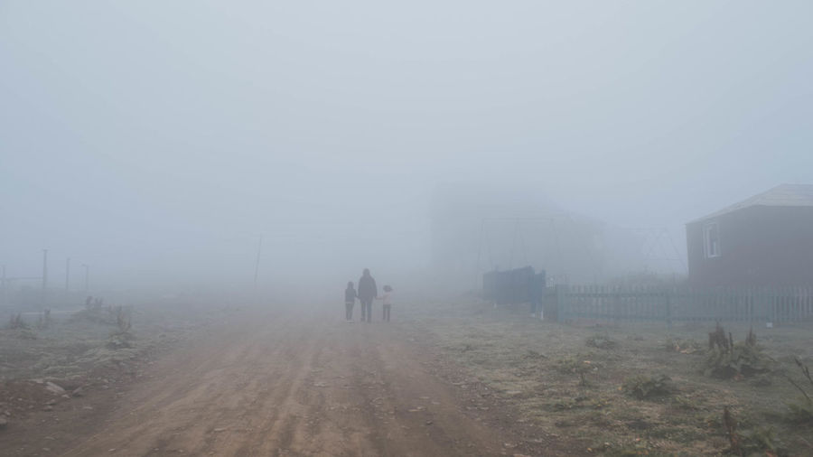 Rear view of people walking on road in foggy weather