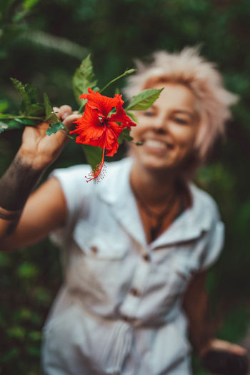 Smiling woman holding red flower