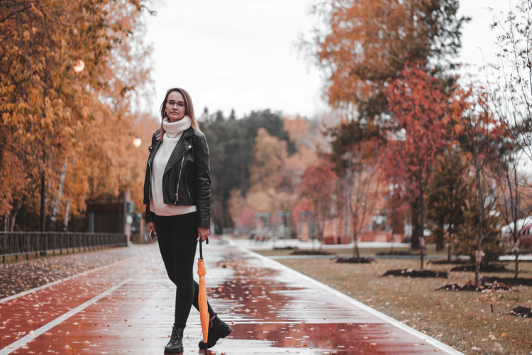 Full length portrait of woman standing in park during autumn