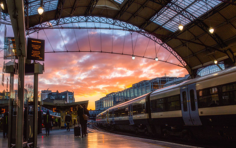 Train at railroad station against cloudy sky during sunset