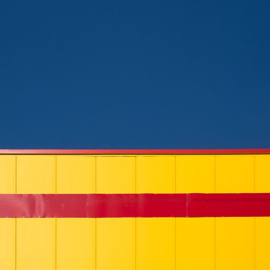 Low angle view of multi colored wall against blue sky