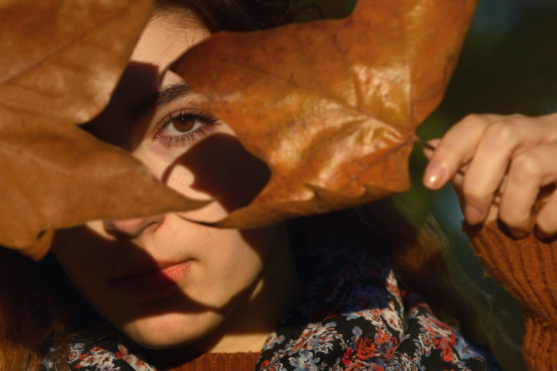 Conceptual autumn leaves and portrait in sunny day in park
