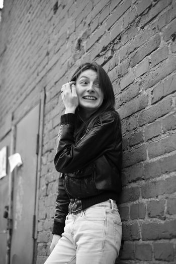 Smiling woman standing against brick wall