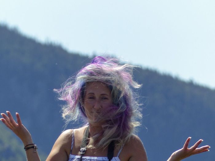 Portrait of woman with colorful hair gesturing while standing against mountain