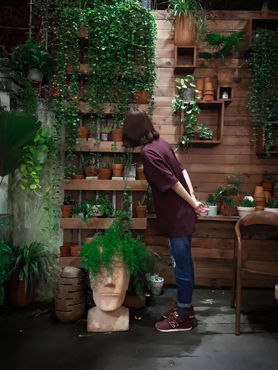 Rear view of a woman standing by potted plants