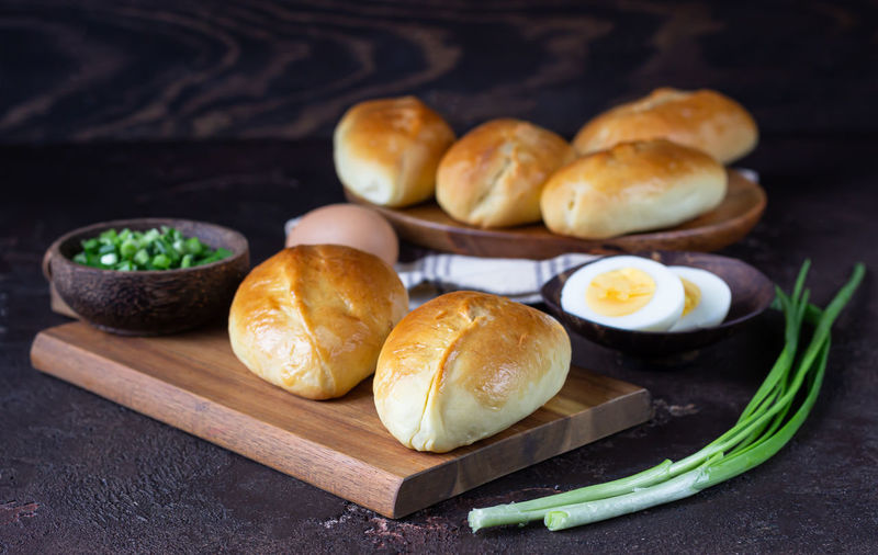 Fresh baked pasties filled with green onion and egg on a wooden board. russian pirozhki.