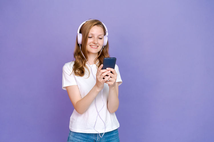 Young woman using mobile phone against blue background