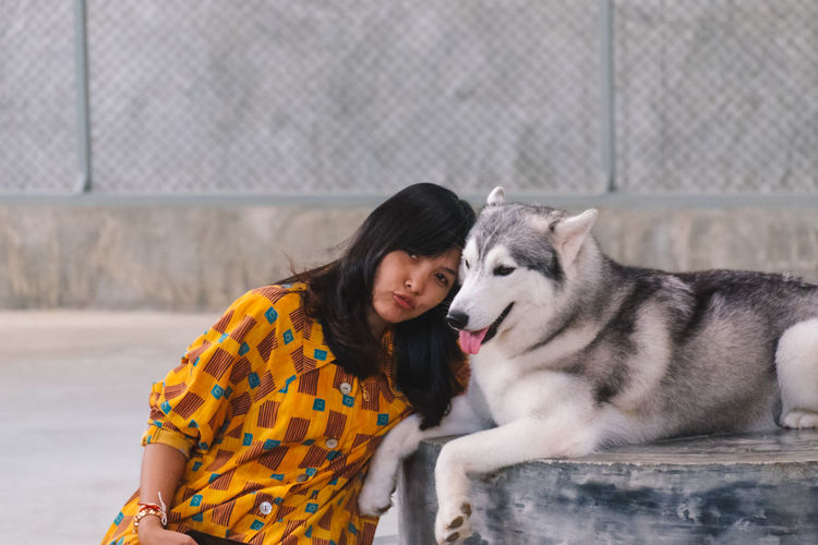 Mid adult woman with siberian husky sitting outdoors