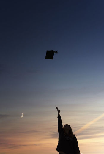 Silhouette of college student tossing graduation cap into the air