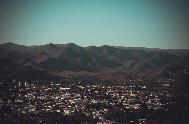 Aerial view of townscape and mountains against clear sky