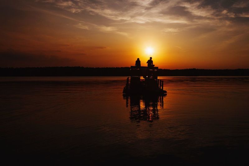 Silhouette of boat in river at sunset