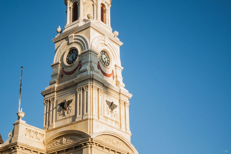 Low angle view of bell tower against clear blue sky