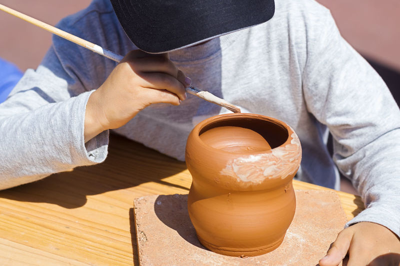 Man painting clay pot at workshop