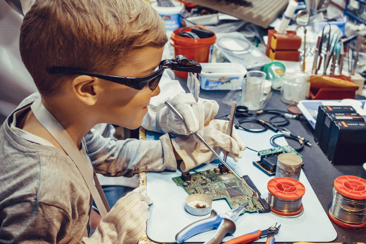 Little boy repairing mother board with engineering teacher in it laboratory.