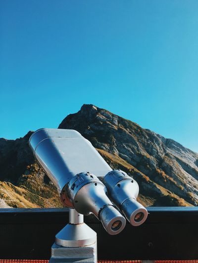 Coin-operated binoculars against clear blue sky