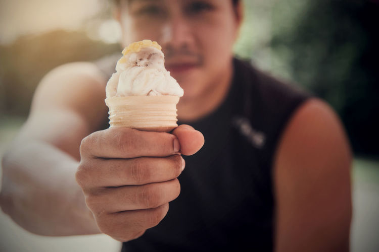 Midsection of man holding ice cream outdoors
