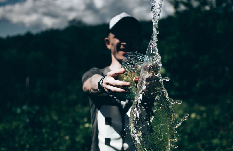 Smiling man throwing water in forest