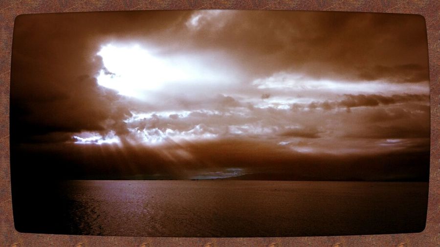 Scenic view of sea against cloudy sky at sunset