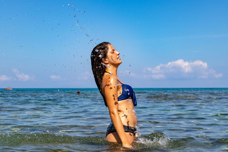 Woman standing in sea against sky