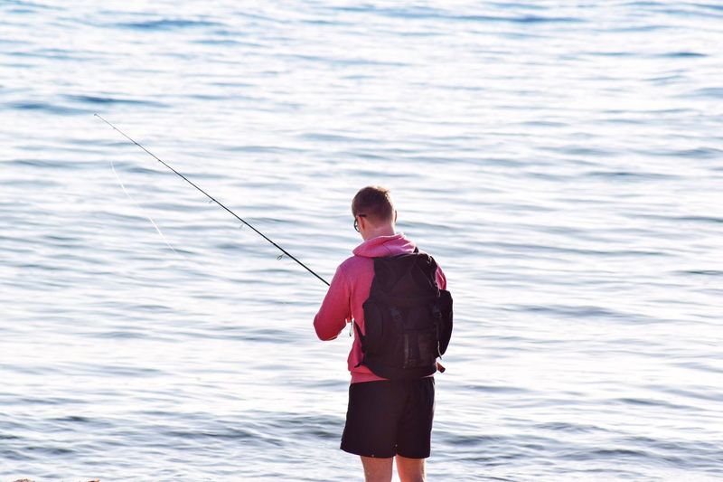 Rear view of man fishing in sea
