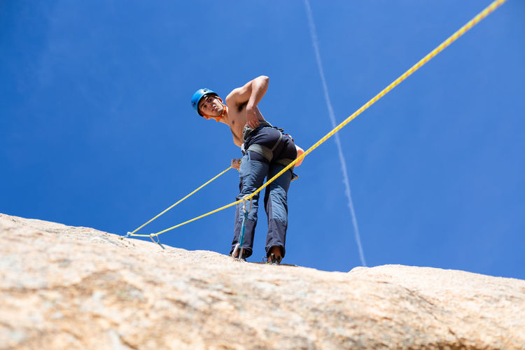 Rear view of shirtless man climbing rock