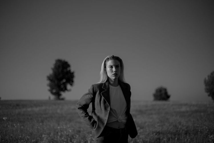 A young woman standing in a field during sunset