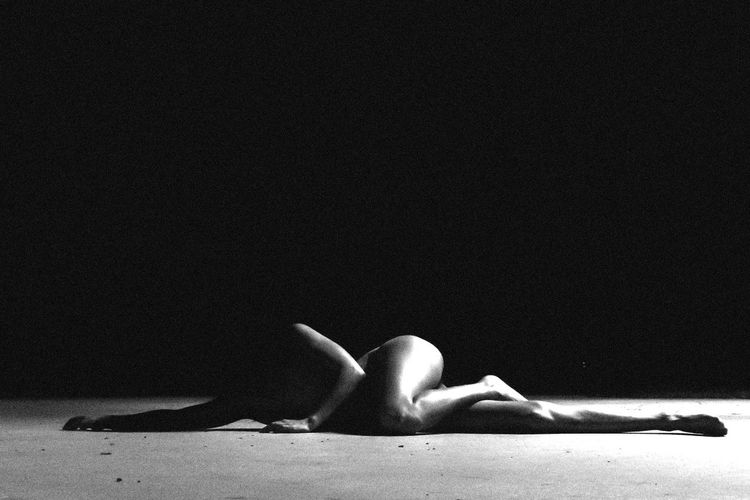 Woman lying down against black background