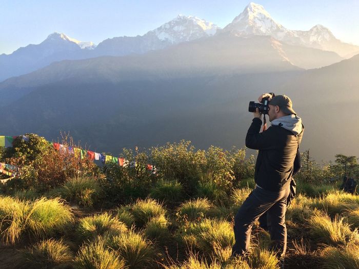 Man photographing through camera while standing on mountain