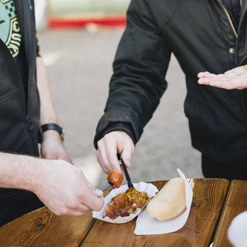 Midsection of men holding food from table