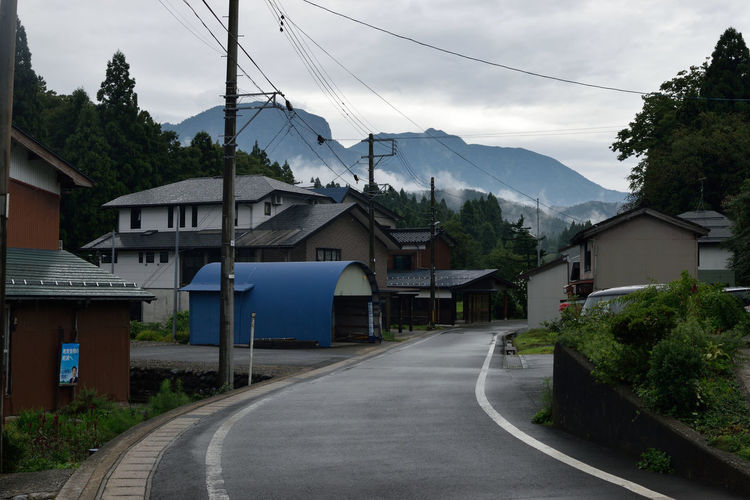 Road by buildings in city against sky