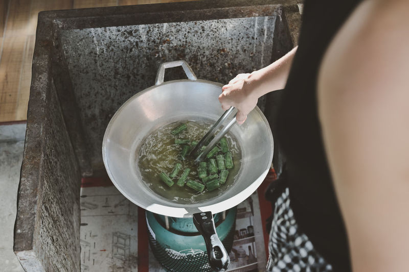 Human part ,woman cooking green vegetable in frying pan