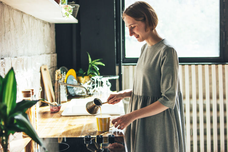 Young woman preparing coffee in kitchen at home