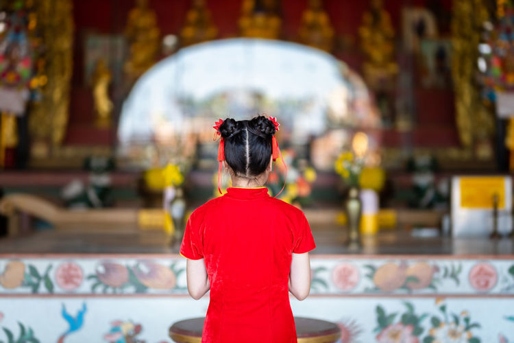 Rear view of girl praying at temple