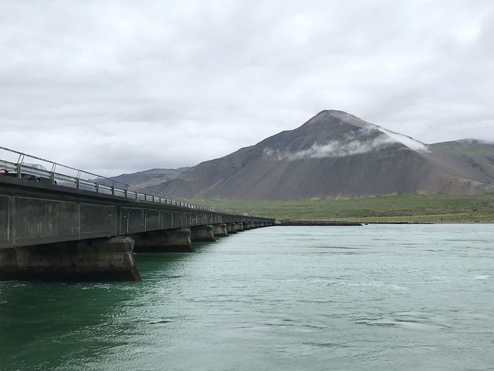 Scenic view of river by mountains against sky