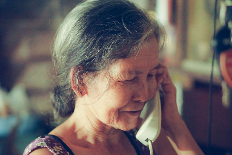 Close-up of senior woman talking on telephone at home