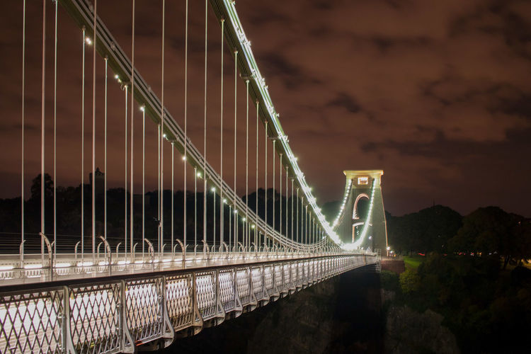 Illuminated suspension bridge against sky at night