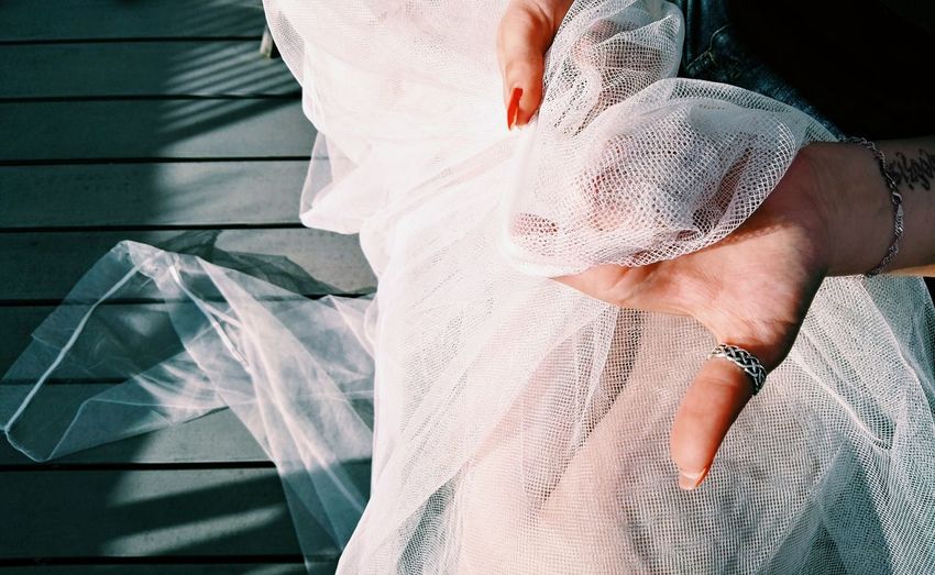 Cropped hands of bride holding white veil