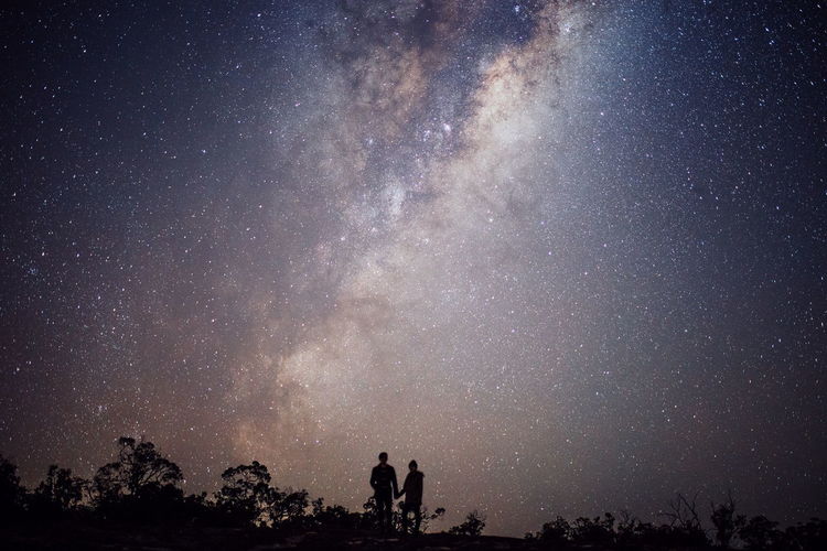 Silhouette of romantic couple under star field sky